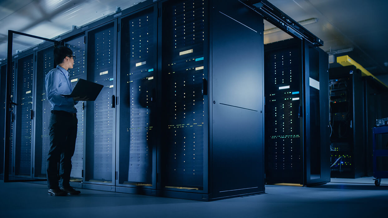 Ein IT-Experte mit Laptop steht vor Server-Racks im Rechenzentrum