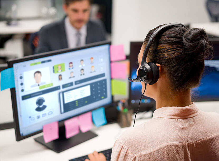Support-Mitarbeiterin kommuniziert mit Kunden über Headset und hat alle relevanten Infos auf einen Blick auf ihrem Bildschirm