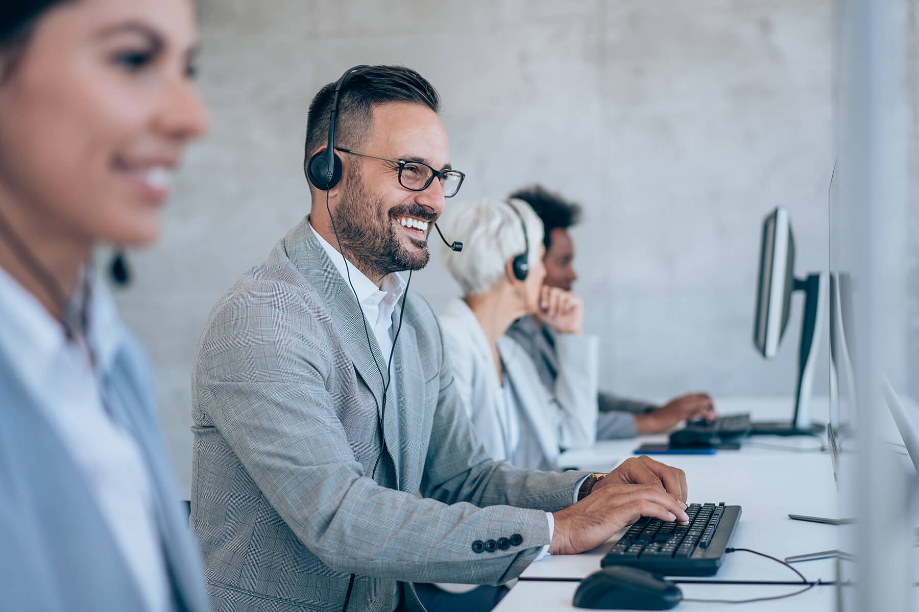 Kundendienst-Team im Büro mit Headsets, am Computer arbeitend, unterstützend und freundlich